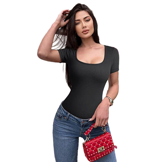 Woman in black top and jeans holding a red studded handbag against a floral background