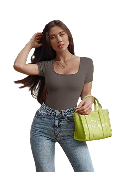 Woman holding a green handbag with text, standing outdoors near a wooden structure.