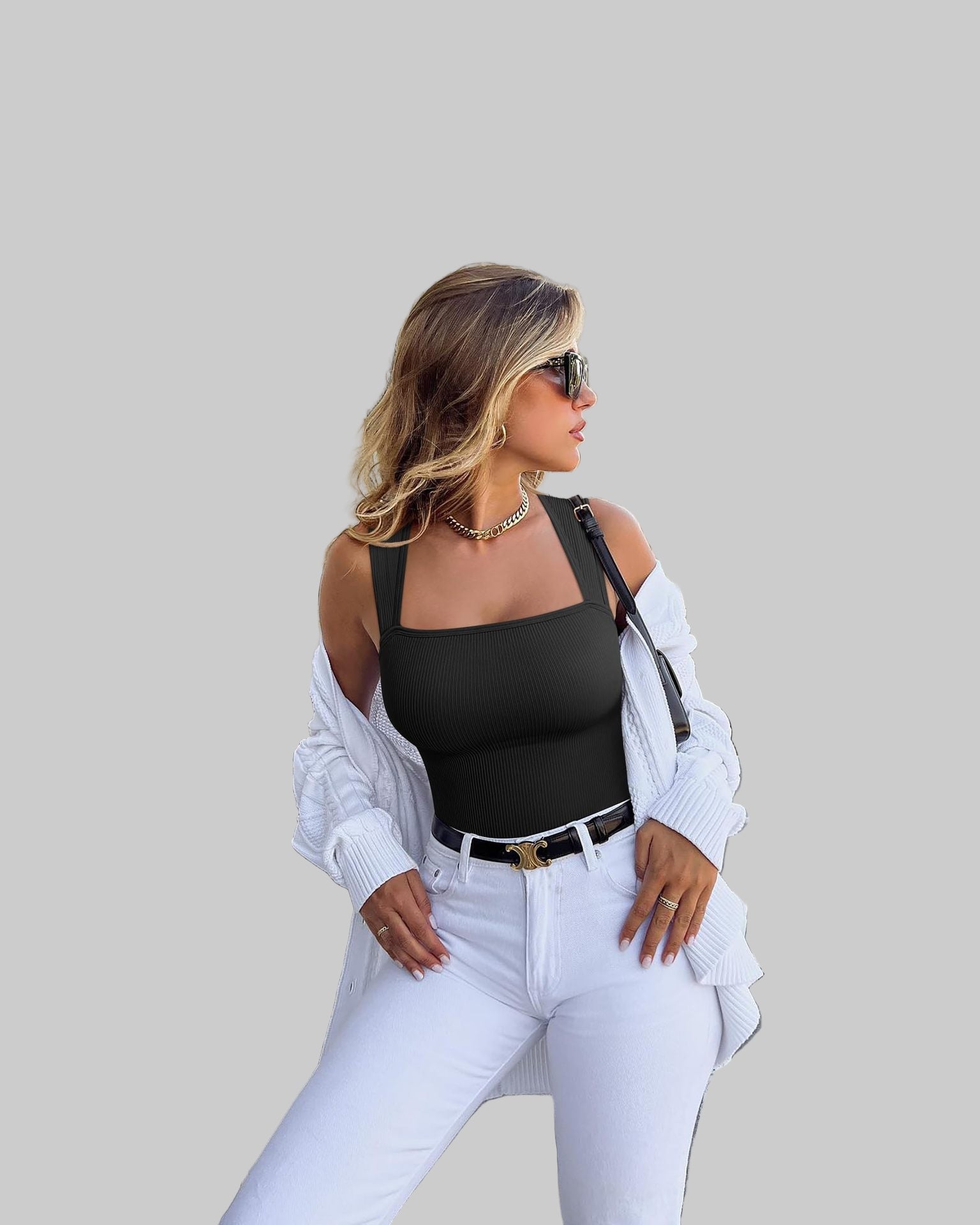 Woman in black top and white pants standing outdoors near classical architecture