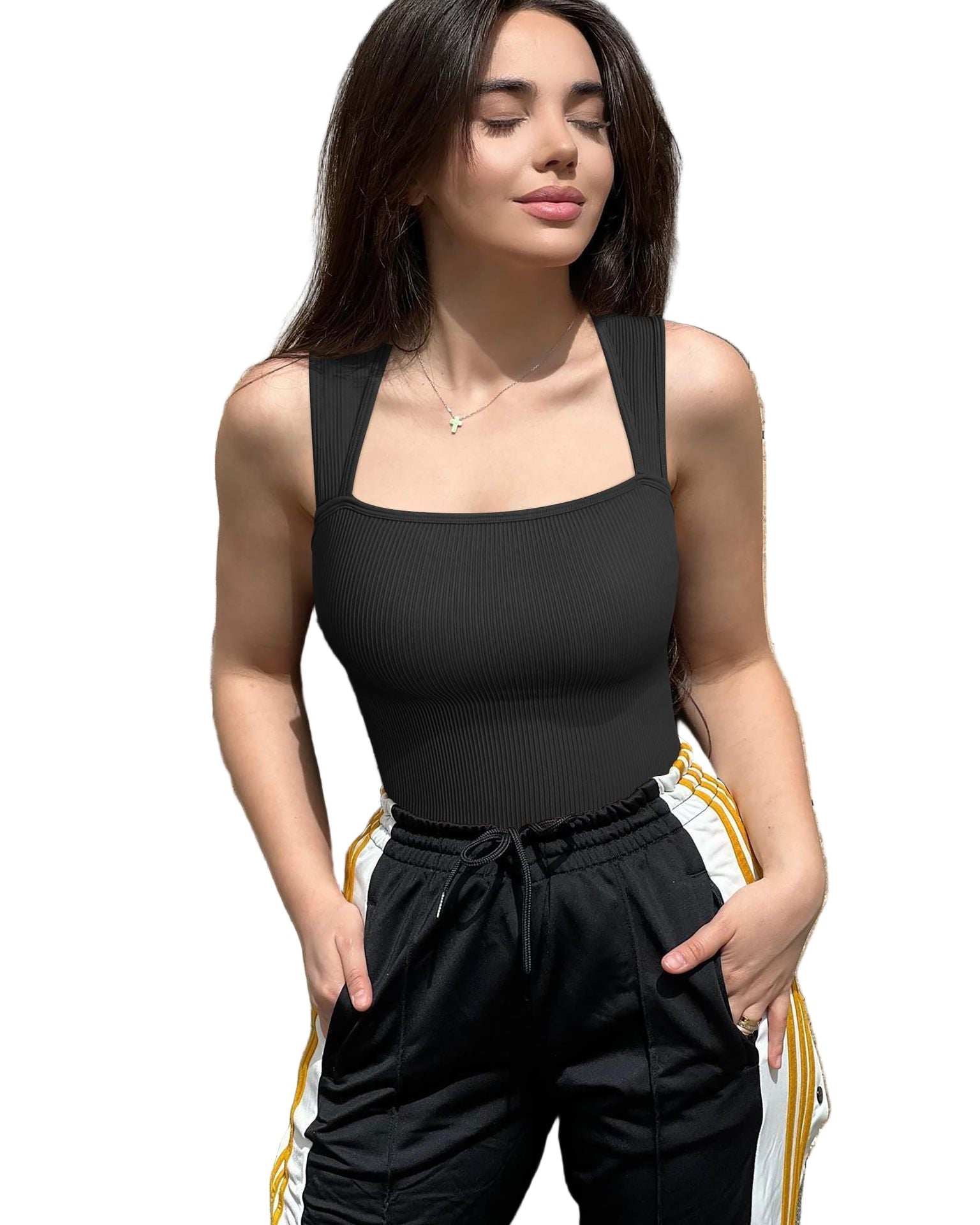 Woman wearing a black sleeveless top and black pants against a stone wall.