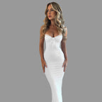 Woman wearing a white strapless dress against a textured beige wall