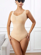 Woman wearing a beige bodysuit in a room with a neutral background