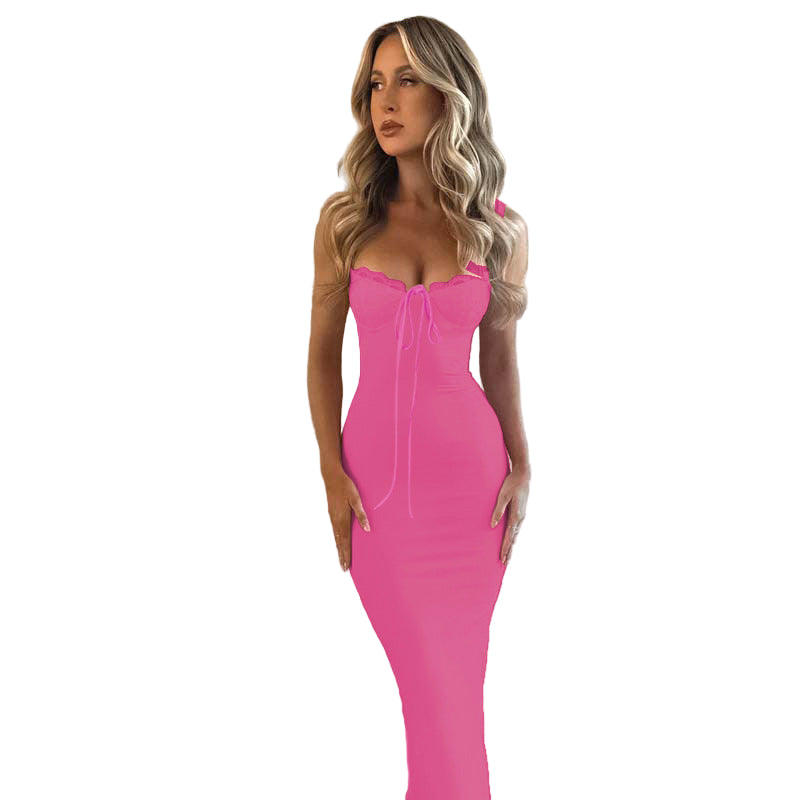 Woman wearing a bright pink dress against a textured beige wall.