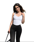 Woman in a white top and black pants standing in front of a green ivy-covered building.