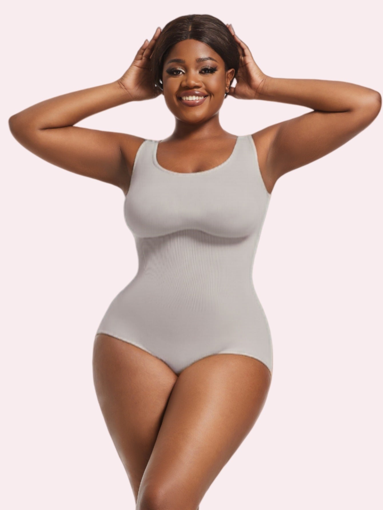 Woman wearing a gray bodysuit against a plain background