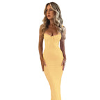 Woman wearing a yellow strapless dress against a textured wall.