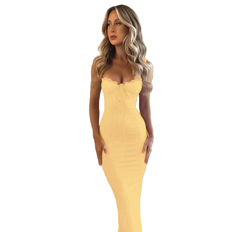 Woman wearing a yellow strapless dress against a textured wall.