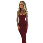 Woman wearing a burgundy dress against a textured beige wall