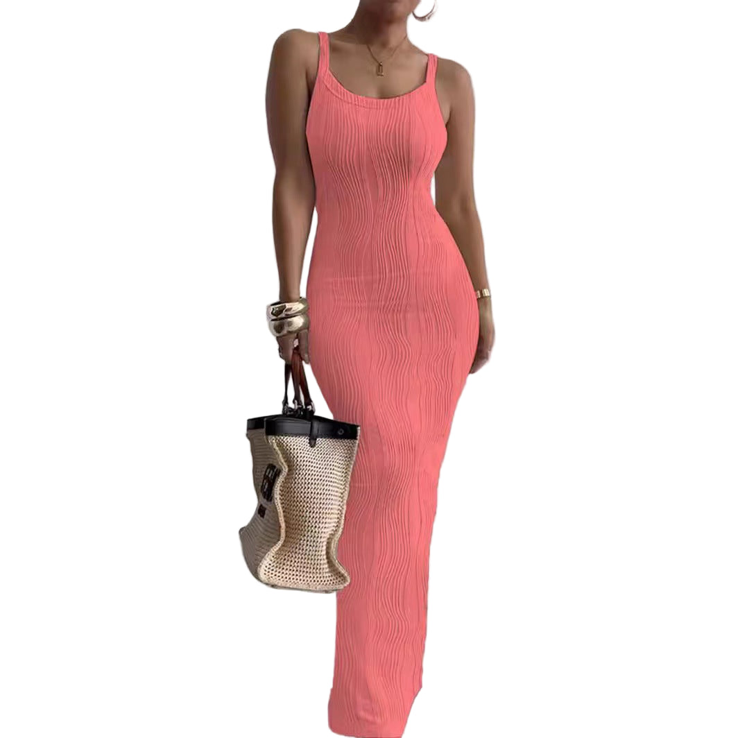 Woman wearing a pink dress holding a straw bag against a plain background