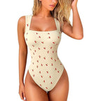 Beige swimsuit with cherry pattern worn by a model on a white background