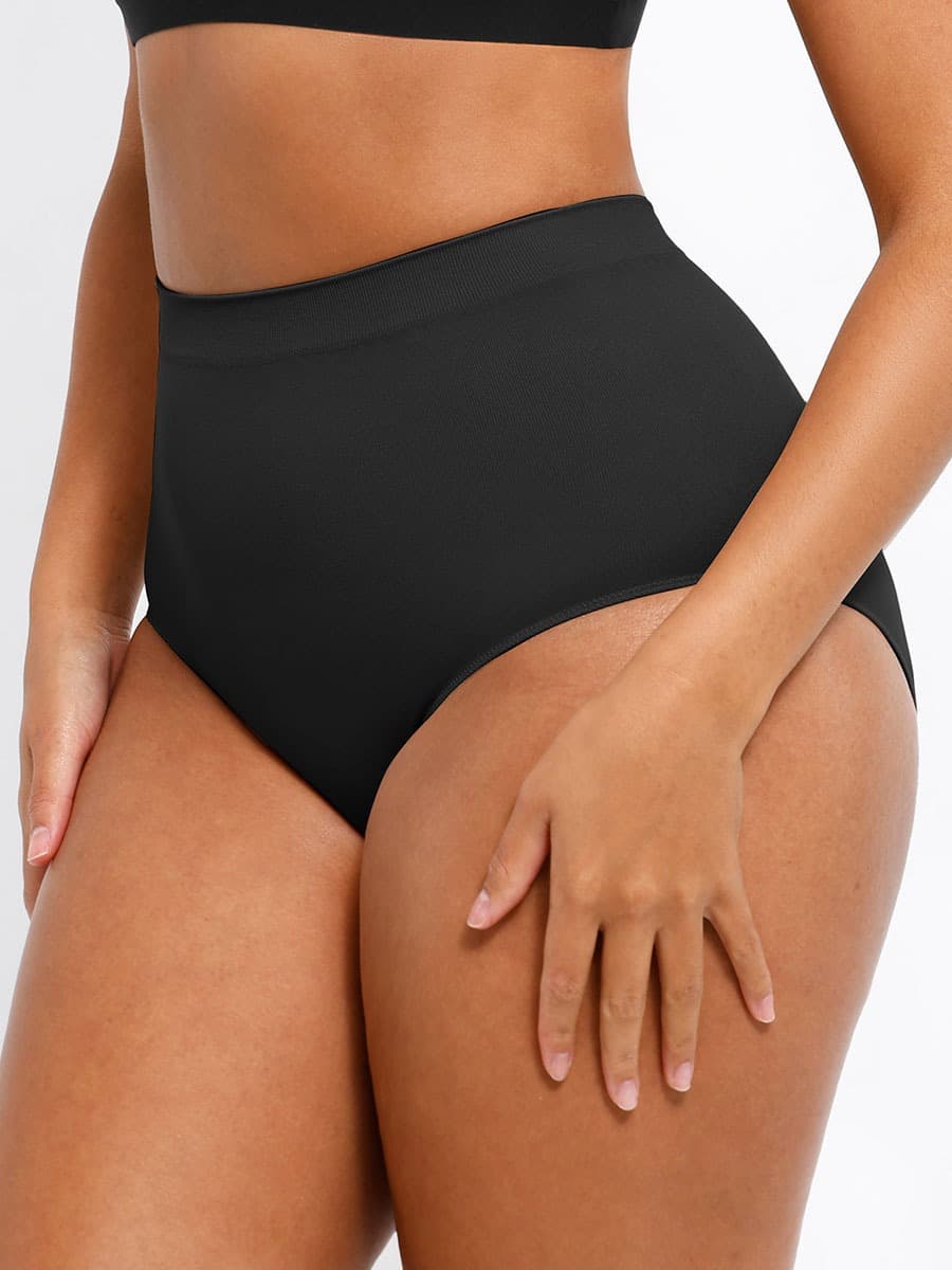 Person wearing black high-waisted bikini bottoms on a white background