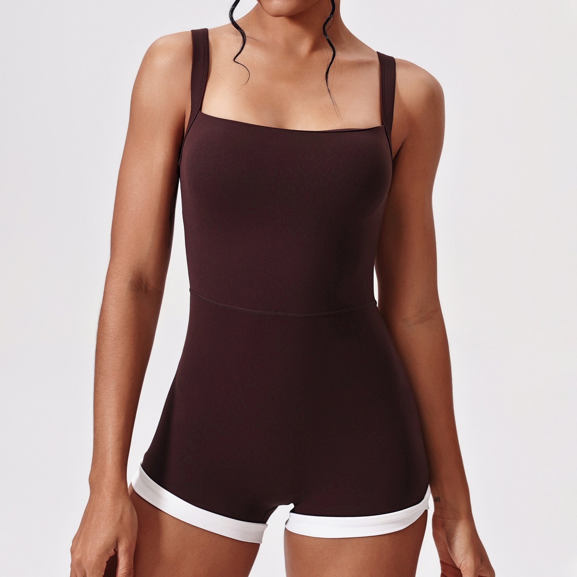 Brown romper with white trim worn by a model on a light gray background