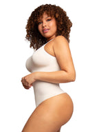 Woman wearing a white bodysuit against a plain background
