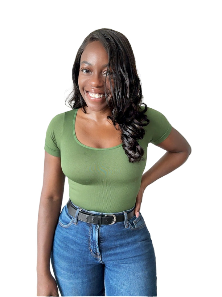 Woman wearing a green top and blue jeans indoors.