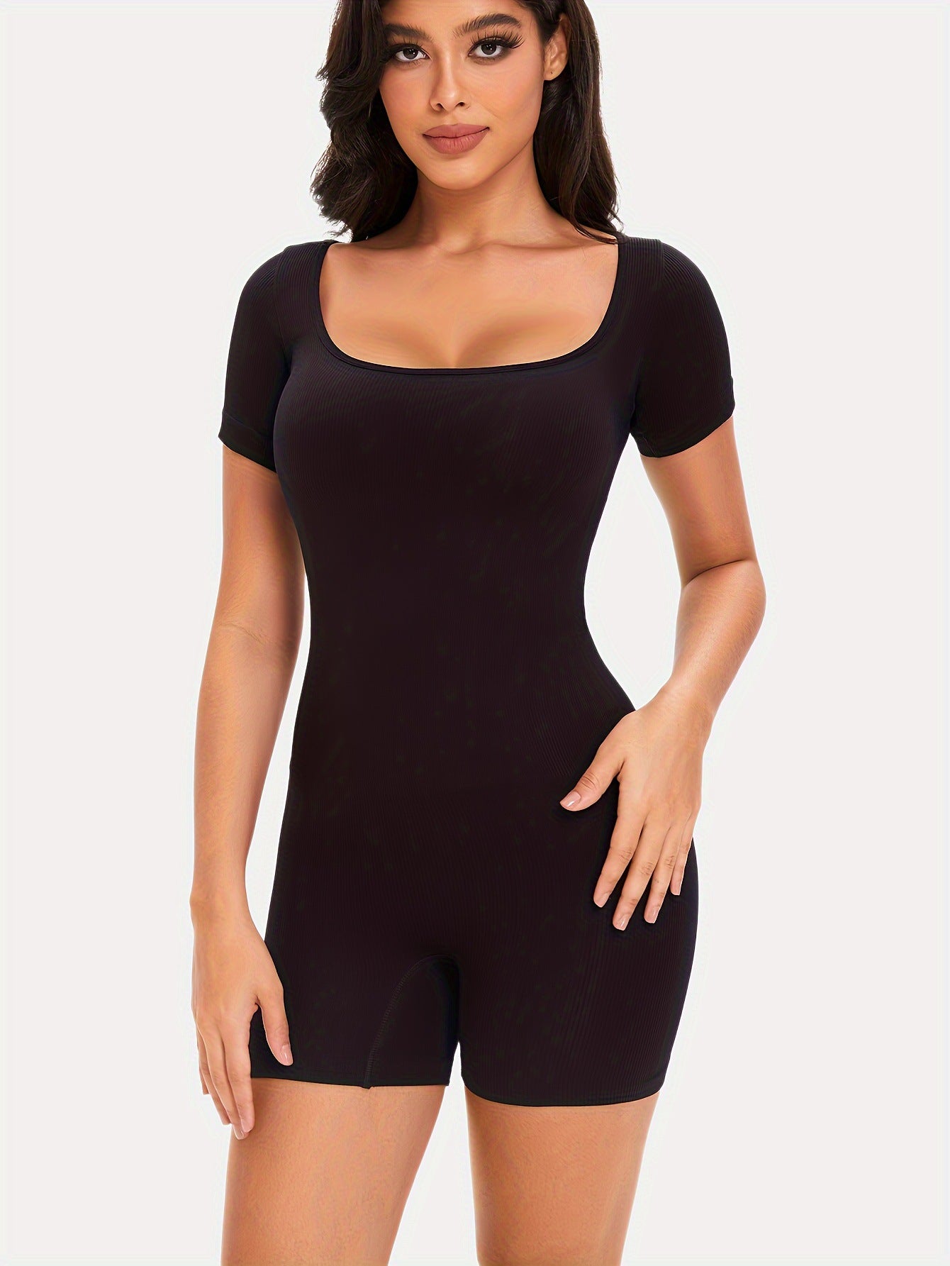 Woman wearing a black bodysuit against a white background