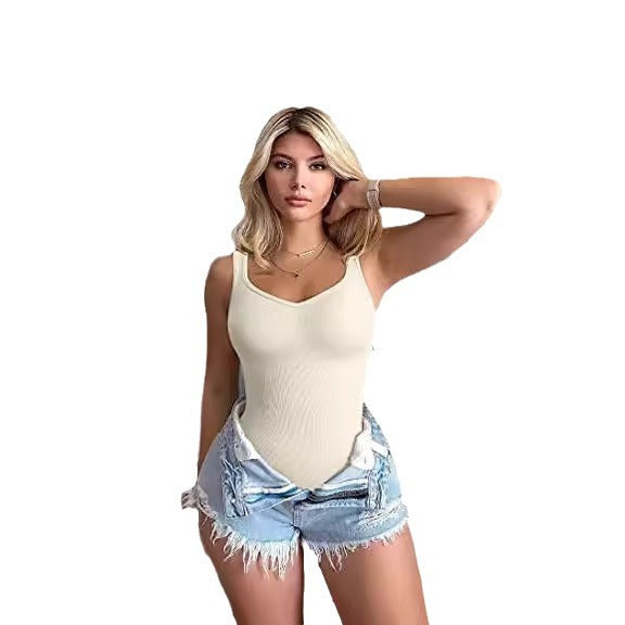 Woman wearing a beige tank top and denim shorts on a white background