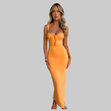 Woman wearing a bright orange dress against a white wall.
