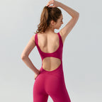 Woman wearing a pink open-back jumpsuit on a light gray background