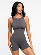 Woman wearing a gray bodysuit against a white background