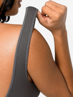 Woman wearing a gray sleeveless dress against a light gray background